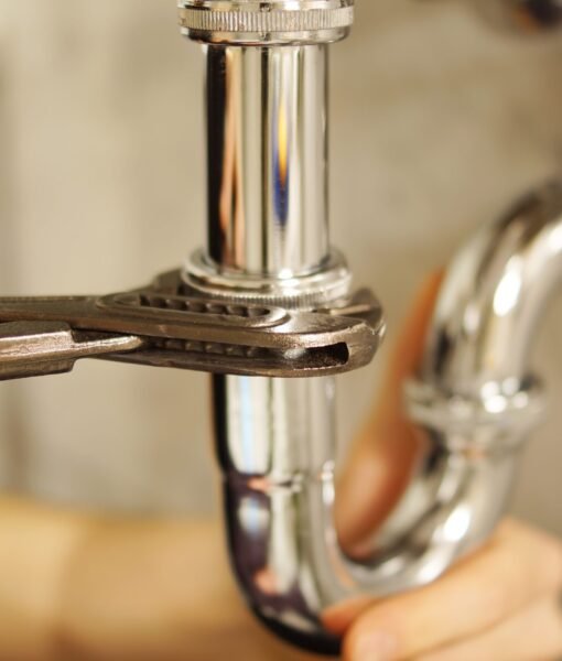 Plumbing repair service. Professional installer with spanner checking pipe.