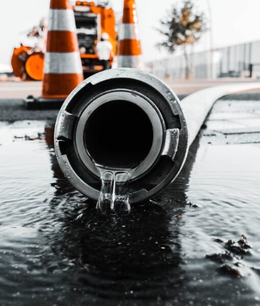 A selective closeup shot of a gray pipe with water coming out its hole
